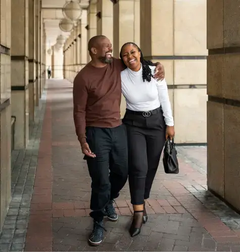 black couple walking in causeway and there is something funky going on with this guy's pant leg that I honestly cannot describe. it almost looks like the AI bot gave him one pant leg from a karate uniform or something.